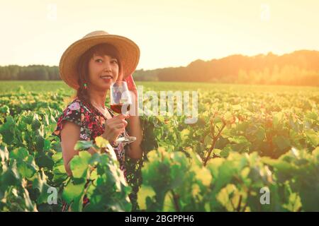 Junge asiatische Frau Weinprobe auf Weinberg in Bordeaux Region während des Sonnenuntergangs in Frankreich Stockfoto