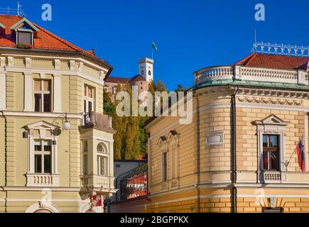 Slowenien, Ljubljana, die Fassade der Philharmonie in Kongresni Trg rechts mit der Burg Ljubljana hoch im Hintergrund. Stockfoto