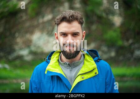 Porträt eines jungen, bärtigen Mannes, auf, vor einem Hintergrund der Tierwelt. Das Konzept von Expedition, Abenteuer und Camping-Leben. Stockfoto