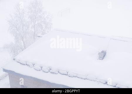 Backsteinhaus mit Schnee auf dem Dach im Winter. Blick aus dem Fenster. Stockfoto