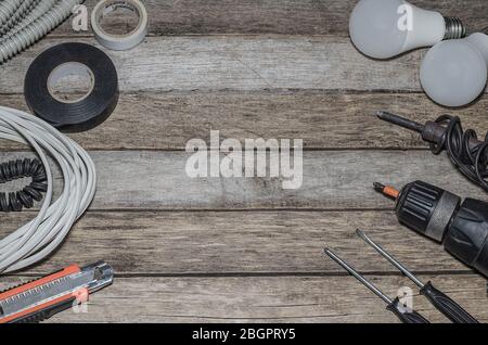 Professionelle Reparaturwerkzeuge für einen Elektriker auf einem alten Holzhintergrund. Flaches Lay. Blick von oben. Stockfoto