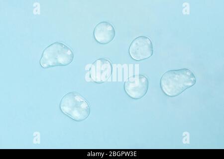 Gepresste kosmetische klare Creme Gel Textur. Nahaufnahme Foto von transparentem Tropfen Hautpflegeprodukt. Hochwertiges transparentes Gel mit Blasen auf blauem Hintergrund. Stockfoto