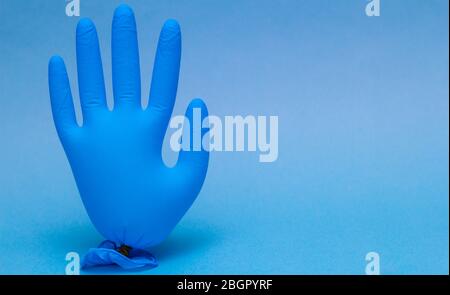 Blauer medizinischer Handschuh aufgeblasen. Auf gelbem Hintergrund mit Kopierbereich. Stockfoto