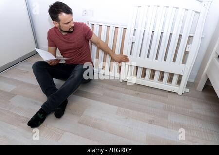 Junger Vater montiert Kinderbett. Stockfoto