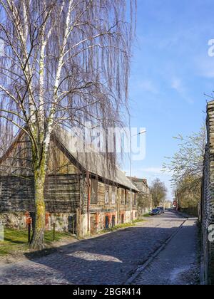 Gepflasterte Straße, altes Holzhaus, Birke in der Nähe des Hauses Stockfoto