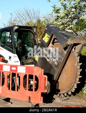 April 2020 - Bobcat-Schlittenlenker-Lader auf Schienen, die mit einem Grabenrad verwendet werden, um Kanäle für Datenkabel im ländlichen Somerset zu verlegen Stockfoto