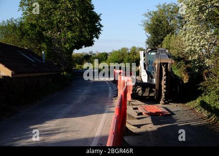 April 2020 - Bobcat-Schlittenlenker-Lader auf Schienen, die mit einem Grabenrad verwendet werden, um Kanäle für Datenkabel im ländlichen Somerset zu verlegen Stockfoto