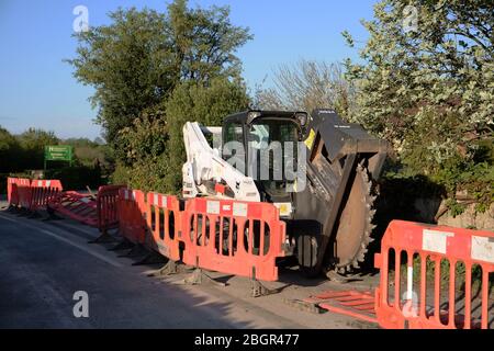 April 2020 - Bobcat-Schlittenlenker-Lader auf Schienen, die mit einem Grabenrad verwendet werden, um Kanäle für Datenkabel im ländlichen Somerset zu verlegen Stockfoto