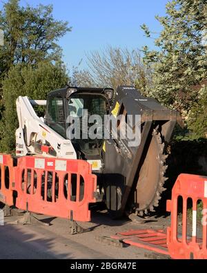 April 2020 - Bobcat-Schlittenlenker-Lader auf Schienen, die mit einem Grabenrad verwendet werden, um Kanäle für Datenkabel im ländlichen Somerset zu verlegen Stockfoto