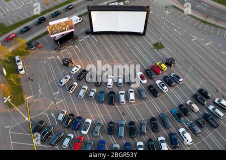 Chemnitz, Deutschland. April 2020. Besucher stehen mit ihren Autos im Drive-in-Kino in Chemnitz. Es ist das erste Mal seit Beginn der Kontaktbeschränkungen, dass es in der Stadt ein Kino gibt. Bis zu 230 Fahrzeuge können auf dem Platz vor dem 200 Quadratmeter Bildschirm oder der 50 Quadratmeter LED Wand parken. Bis zum 25. Juni gibt es jeden Tag um 17 Uhr einen Kinder- und Familienfilm und das Abendprogramm um 20 Uhr. Freitags und samstags gibt es ab 23:00 Uhr einen Mitternachtsfilm. (Luftaufnahme mit Drohne) Quelle: Jan Woitas/dpa-Zentralbild/dpa/Alamy Live News Stockfoto