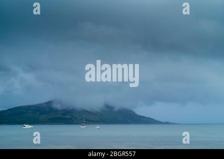 Nebelgraue Szene - Vergnügungsboote, Yachten und Kreuzer, die in der Bucht von Lamlash auf der Isle of Arran, Schottland, festgemacht sind Stockfoto