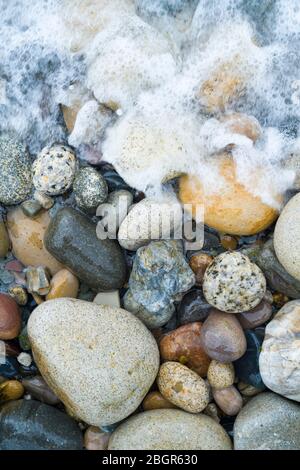 Kieselsteine in Pastelltönen bilden an der Küste der Isle of Arran, Schottland, kurvige Formen Stockfoto