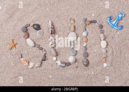 Wort Sonne aus Muscheln und Steinen auf Sand Stockfoto