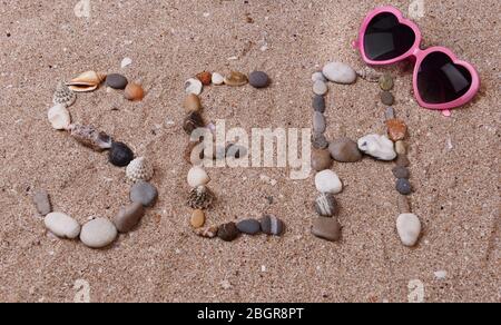 Wort Meer aus Muscheln und Steinen auf Sand Stockfoto