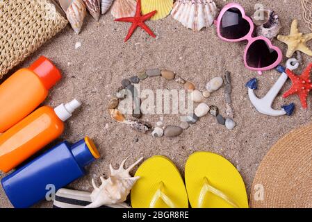 Form von Fischen aus Muscheln und Steinen auf Sand mit Strand-Accessoires Stockfoto