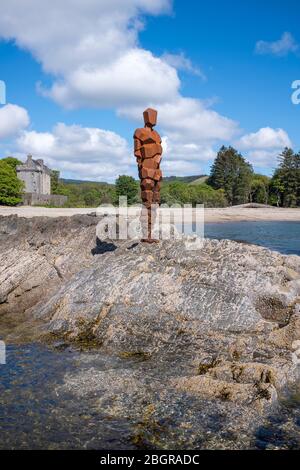 Antony Gormley Skulptur GRIFF einer abstrakten menschlichen Form Blick über Saddell Bay, Kilbrannan Sound zu Arran, Saddell Castle im Hintergrund in Kinty Stockfoto