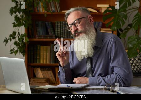 Konzept des Fernlernens. Lehrer Tutor Blick auf Laptop und im Gespräch mit dem Gesprächspartner auf Video-Kommunikation, selektive Fokus Stockfoto