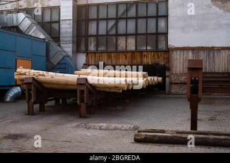 Die hölzernen Balken auf dem Sägewerk, vorbereitet, auf der Schneide zu sägen. Holzwirtschaft. Ein Haufen von Baumstämmen liegt auf einer Plattform. Bearbeitung von Holz im Sägewerk. Stockfoto