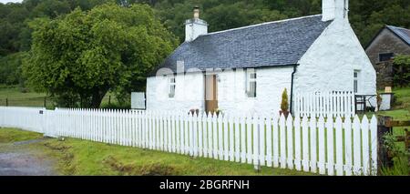 Malerisches traditionelles weiß getünchtes Cottage mit weißem Zaun und gefliestem Dach in Appin, Argyll und Bute, Schottland Stockfoto