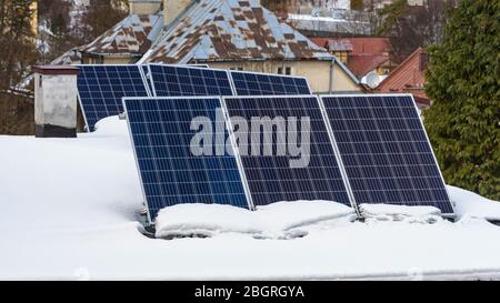 Solarpaneele von Photovoltaikkraftwerk auf dem schneebedeckten Dach Stockfoto