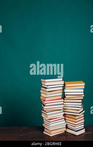 Viele Stapel von Lehrbüchern in der Universitätsbibliothek auf grünem Hintergrund Stockfoto