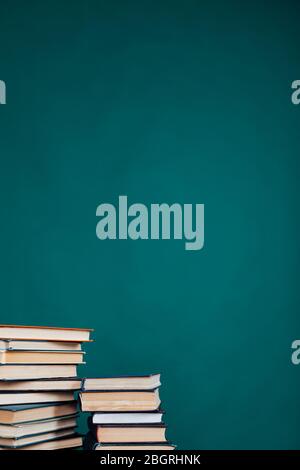 Viele Stapel von Lehrbüchern in der Universitätsbibliothek auf grünem Hintergrund Stockfoto