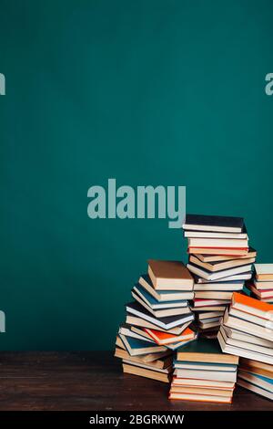 Viele Stapel von Lehrbüchern in der Universitätsbibliothek auf grünem Hintergrund Stockfoto