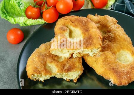 Navajo Brot, Tomaten Kirsche, grüner Salat auf dem schwarzen Teller Nahaufnahme. Leckeres indisch-amerikanisches navajo-Fladenbrot. Stockfoto