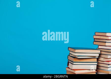 Eine Menge Stapel von Lehrbüchern in der Hochschulbibliothek auf einem blauen Hintergrund Stockfoto