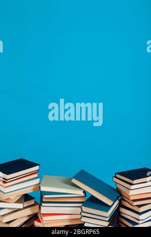 Eine Menge Stapel von Lehrbüchern in der Hochschulbibliothek auf einem blauen Hintergrund Stockfoto