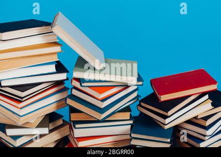 Eine Menge Stapel von Lehrbüchern in der Hochschulbibliothek auf einem blauen Hintergrund Stockfoto