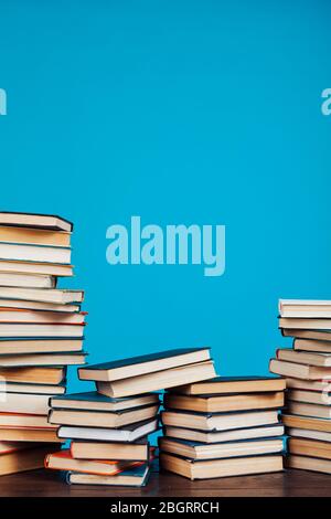 Eine Menge Stapel von Lehrbüchern in der Hochschulbibliothek auf einem blauen Hintergrund Stockfoto