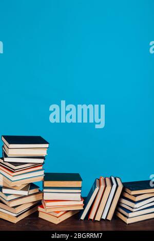 Eine Menge Stapel von Lehrbüchern in der Hochschulbibliothek auf einem blauen Hintergrund Stockfoto