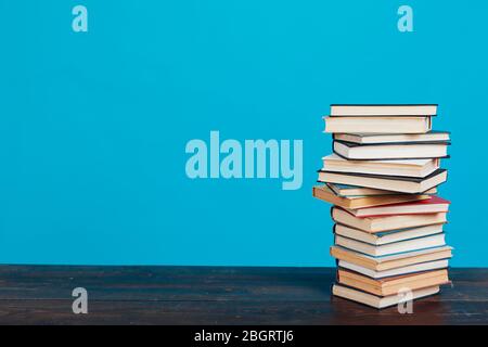 Eine Menge Stapel von Lehrbüchern in der Hochschulbibliothek auf einem blauen Hintergrund Stockfoto