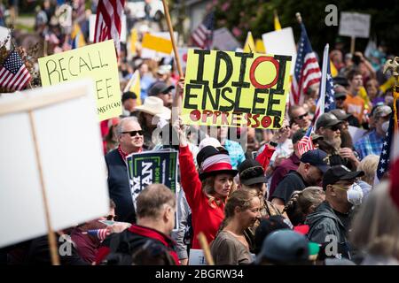 Eine Frau hält ein Schild, das Washington State Governor Jay Inslee einen „Unterdrücker“ bei einem Protest gegen die Stay-at-Home-Beschränkungen während der COVID-19 pa nennt Stockfoto