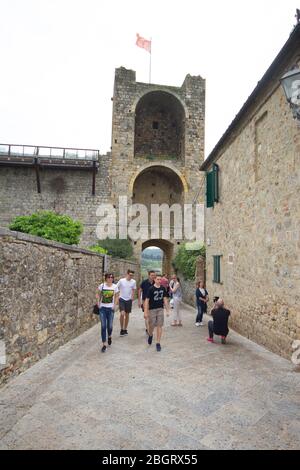 Straße im Dorf Monteriggioni unter Touristen, mittelalterliche Mauern und Türme Stockfoto