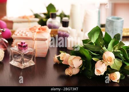 Schöne Rosen, Parfüms auf dem Tisch in der Nähe des Spiegels Stockfoto