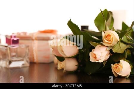 Schöne Rosen, Parfüms auf dem Tisch in der Nähe des Spiegels Stockfoto