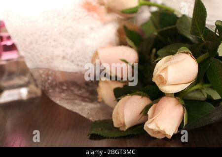 Schöne Rosen, Parfüms auf dem Tisch in der Nähe des Spiegels Stockfoto