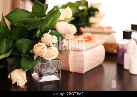 Schöne Rosen, Parfüms auf dem Tisch in der Nähe des Spiegels Stockfoto