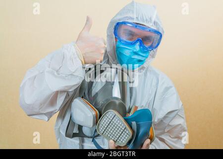Arzt trägt weißen Schutzanzug und Stethoskop voll Gesicht Atemschutzmasken in der Hand isoliert. Stockfoto