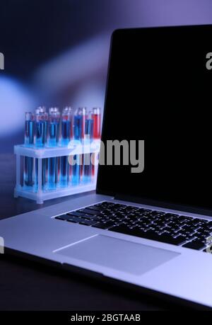 Laptop mit Reagenzgläsern in einem Labor auf blauem Hintergrund Stockfoto