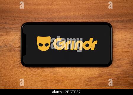 Ein Smartphone mit Grindr-Logo liegt auf einem einfachen Holztisch (nur redaktionelle Verwendung). Stockfoto