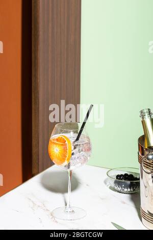 Gin Tonic Cocktail, garniert mit orangefarbenen Scheiben, farbenfroher Hintergrund Stockfoto