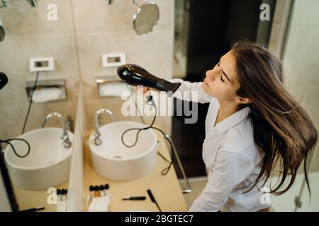 Frau, die ihr Haar Styling mit einer Bürste zu Hause.Bad Haar day.Daily Frisur Vorbereitung Routine.Heat Schäden, Spliss, trockenes Haar Loss.Getting bereit Stockfoto