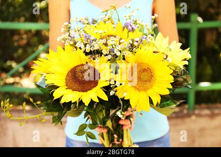 Schöner Strauß Sonnenblumen in weiblichen Händen Stockfoto