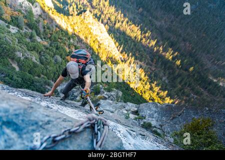 Mann mit Hut schaut hinunter Schropfseil mit Rucksack auf El Capitan Stockfoto