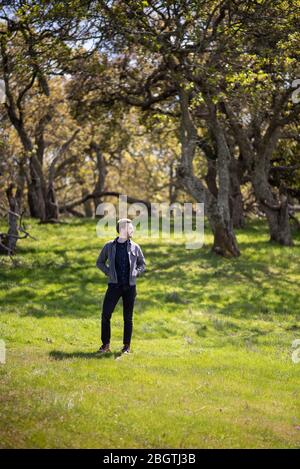 Ganzkörper-Porträt des jungen Mannes lässig im Freien mit Bäumen gekleidet Stockfoto