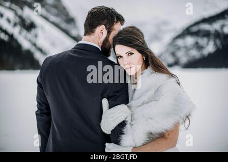 Braut in Brautkleid greift Bräutigam Arm nach verheiratet auf gefrorenem See Stockfoto