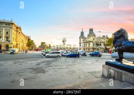 Ein farbenfroher Sonnenaufgang über einer bronzenen Löwenstatue vom Columbus-Denkmal am La Rambla-Kreisverkehr in Barcelona, Spanien. Stockfoto